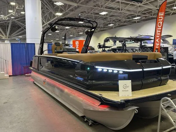 Slide: The Image of 2025 Princecraft Vogue 25 RL pontoon boat displayed at an indoor boat show. - 5