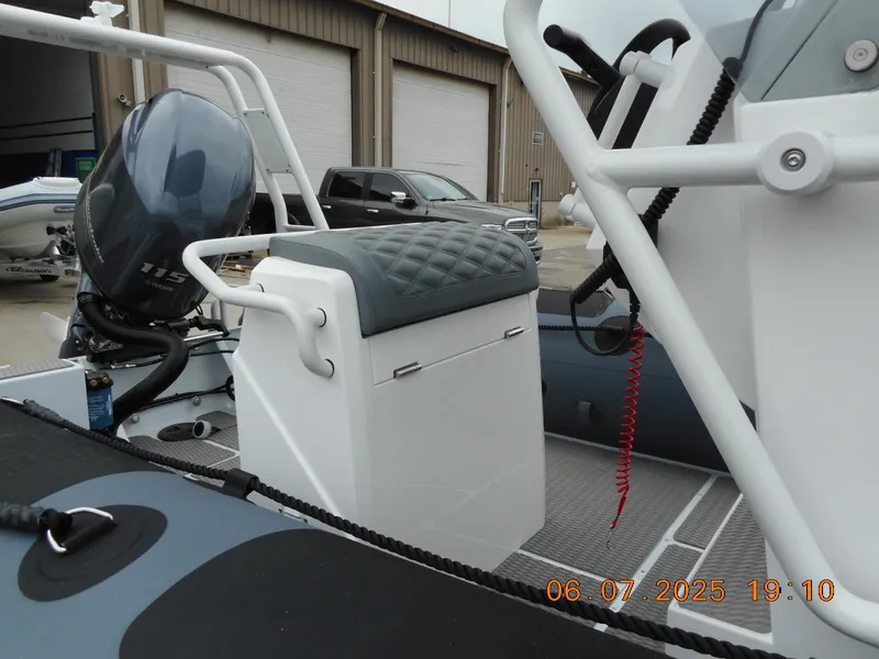 Slide: The Image of 2025 Highfield Patrol 540 boat interior with seating and motor, docked near storage facility. - 4