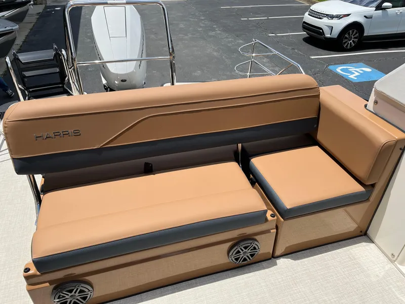 Slide: The Image of 2026 Harris Grand Mariner 250 boat seating with tan and gray upholstery in a parking lot. - 13