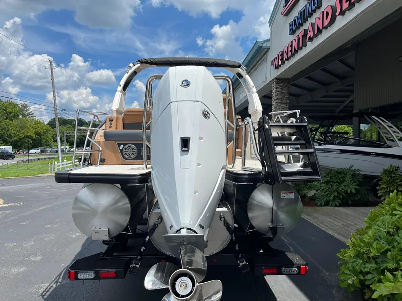 Slide: The Image of 2026 Harris Grand Mariner 250 boat rear view at dealership under blue sky. - 2