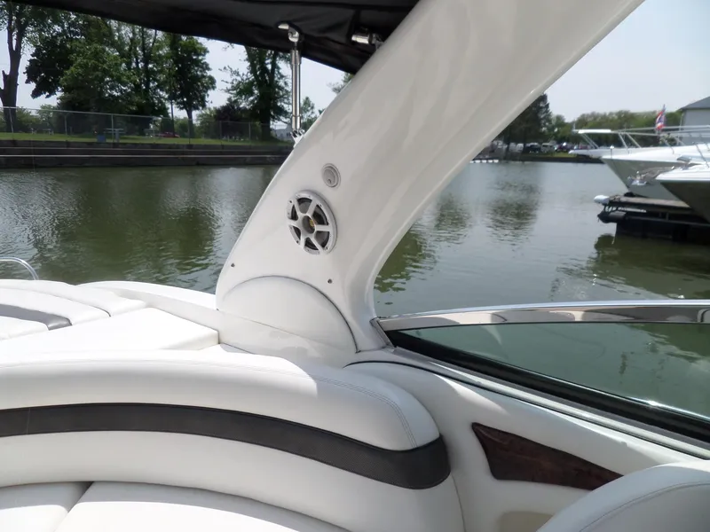 Slide: The Image of 2005 Sea Ray 290 SS boat interior with white seating and speaker, docked by a calm lake. - 14