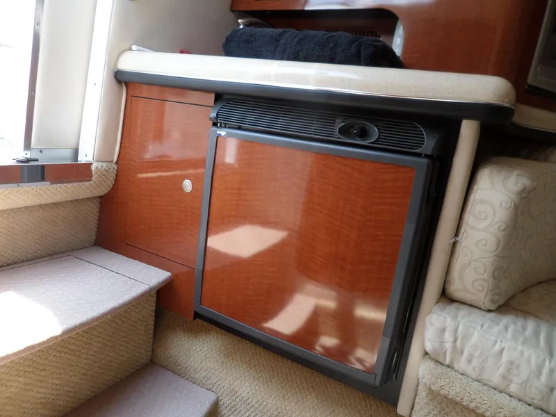 Slide: The Image of 2005 Sea Ray 290 SS interior with compact fridge and wooden cabinetry. - 32