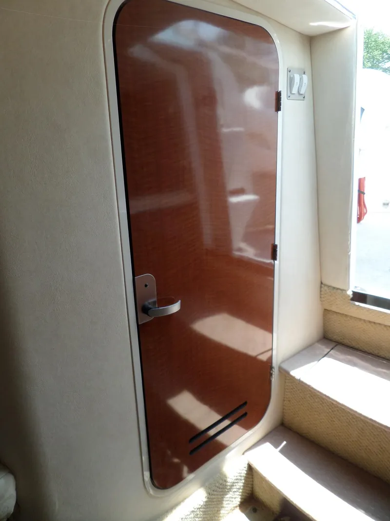 Slide: The Image of 2005 Sea Ray 290 SS cabin door with wooden finish and metal handle. - 38