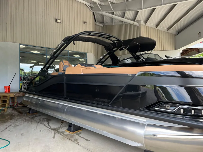 Slide: The Image of 2026 Harris Grand Mariner 250 pontoon boat in showroom, featuring sleek black design and tan seating. - 3