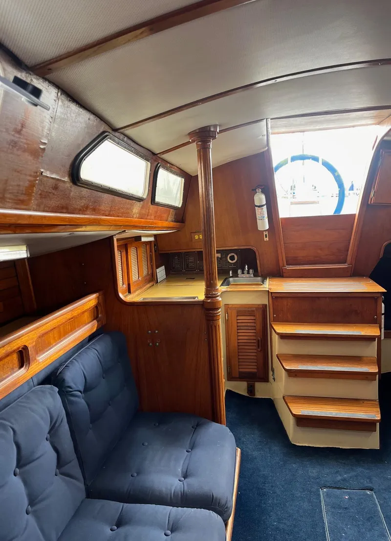 Slide: The Image of 1978 Islander Sloop 36 cabin interior with wooden finish and blue cushions. - 10