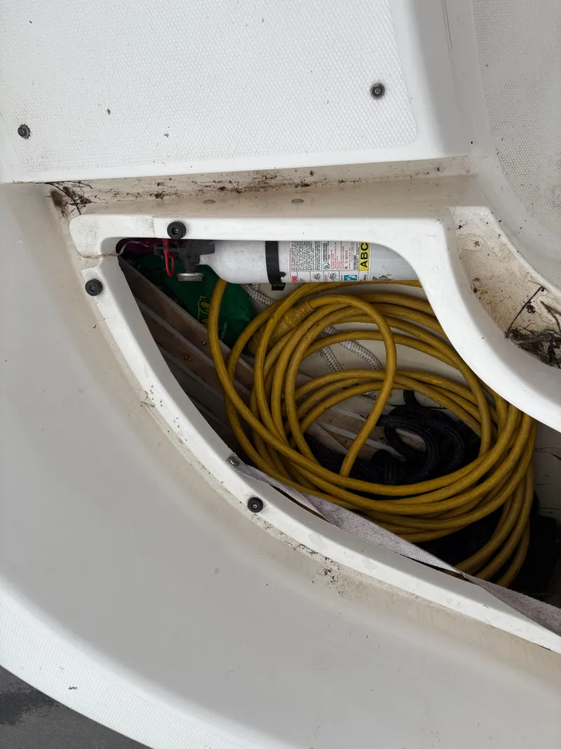 Slide: The Image of Storage compartment of a 1997 Hunter 310 boat with coiled yellow cable and fire extinguisher. - 16