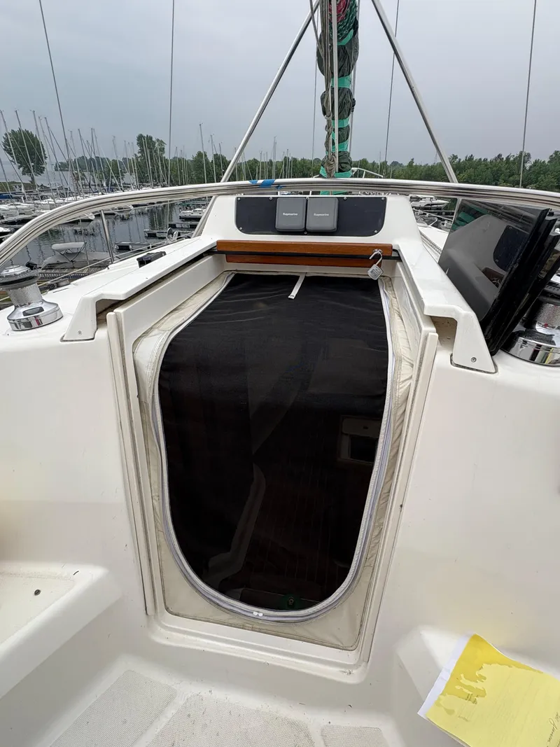 Slide: The Image of 1997 Hunter 310 sailboat cockpit with open cabin entrance, marina background. - 18