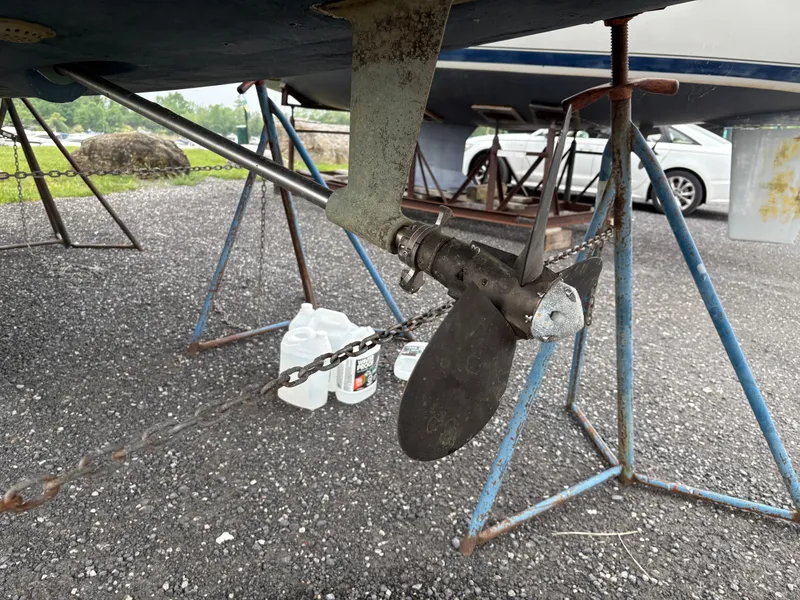 Slide: The Image of Propeller of a 1997 Hunter 310 sailboat on stands, with jugs and a car nearby. - 4