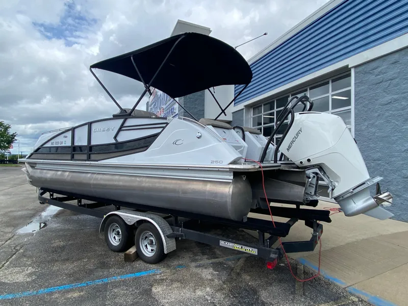Slide: The Image of 2020 Crest Savannah 250 SLRC pontoon boat on trailer, parked outside a building. - 40