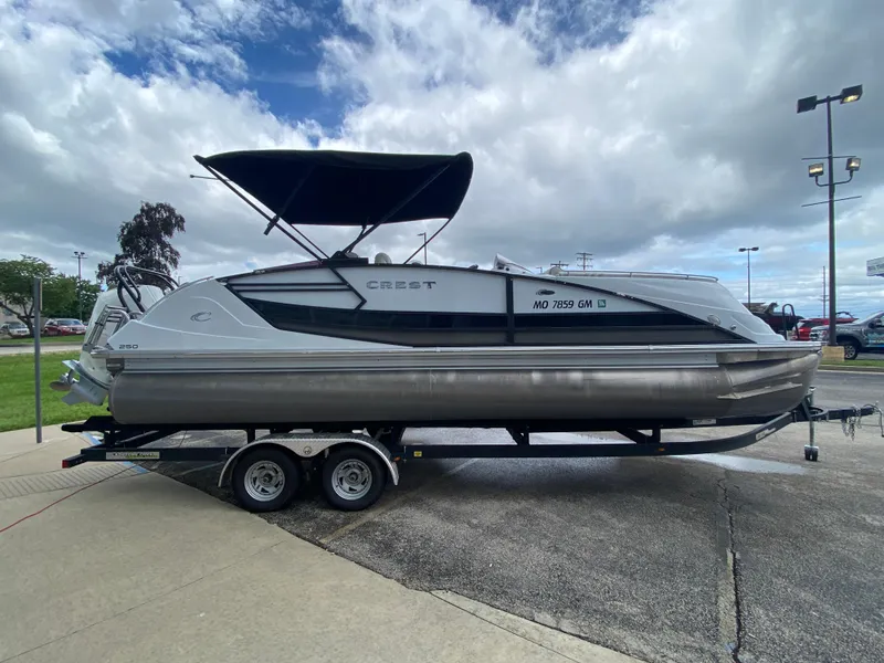Slide: The Image of 2020 Crest Savannah 250 SLRC pontoon boat on trailer, parked outdoors under cloudy sky. - 42