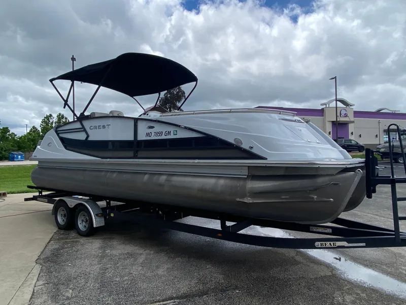Slide: The Image of 2020 Crest Savannah 250 SLRC pontoon boat on trailer, parked outdoors under cloudy sky. - 43