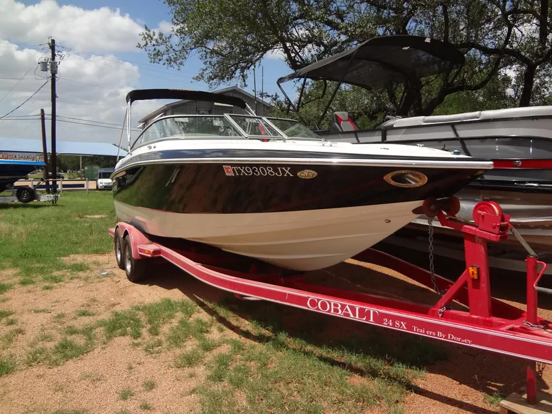 The Image of 2004 Cobalt 240 boat on red trailer, parked outdoors under a clear sky. - 0