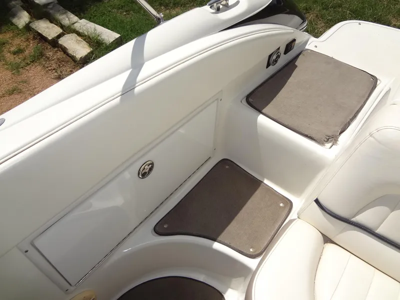 Slide: The Image of 2004 Cobalt 240 boat interior with white seating and storage compartments. - 26