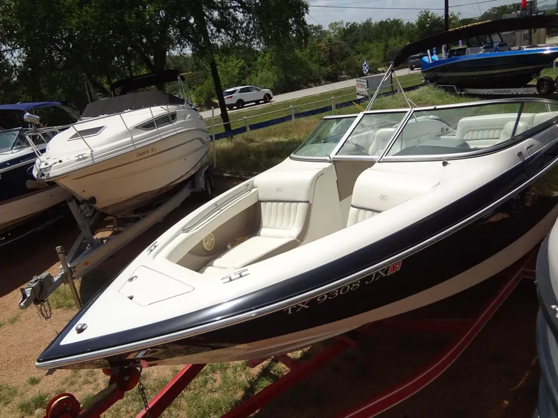 Slide: The Image of 2004 Cobalt 240 boat on trailer, parked outdoors, with other boats nearby. - 7