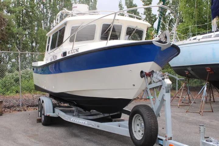 Slide: The Image of 1995 SeaSport 2400 Explorer boat on trailer, blue and white, parked outdoors. - 10