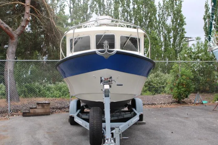 Slide: The Image of 1995 SeaSport 2400 Explorer boat on trailer, parked outdoors with trees in background. - 11