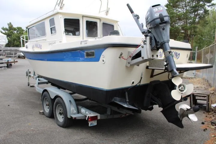 Slide: The Image of 1995 SeaSport 2400 Explorer boat on trailer with outboard motor, parked outdoors. - 13