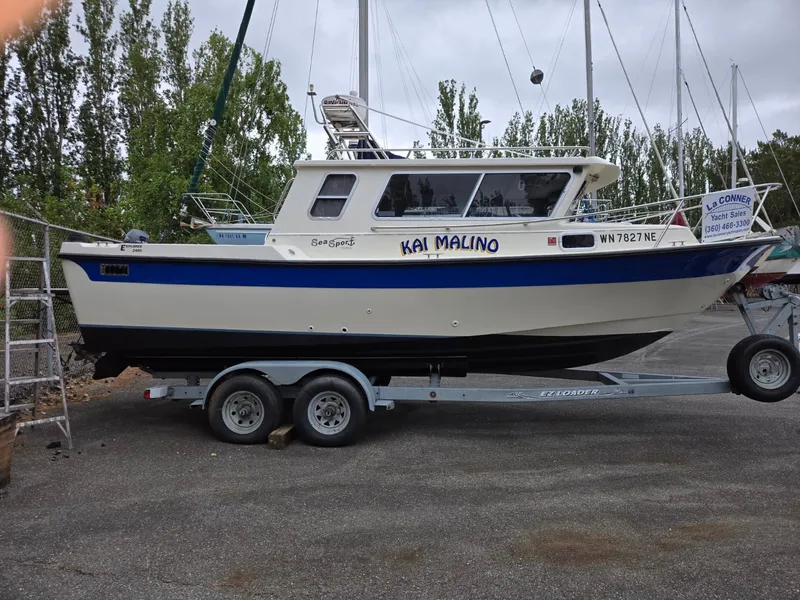 Slide: The Image of 1995 SeaSport 2400 Explorer boat on trailer, named "Kai Malino," parked outdoors. - 3