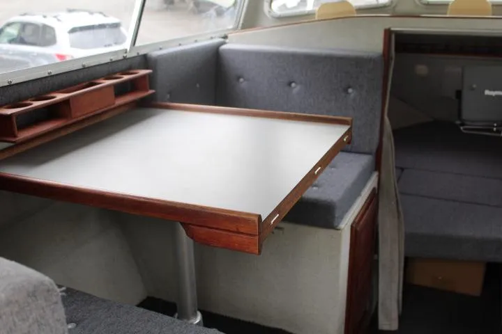 Slide: The Image of Interior of a 1995 SeaSport 2400 Explorer boat with a foldable table and seating area. - 43