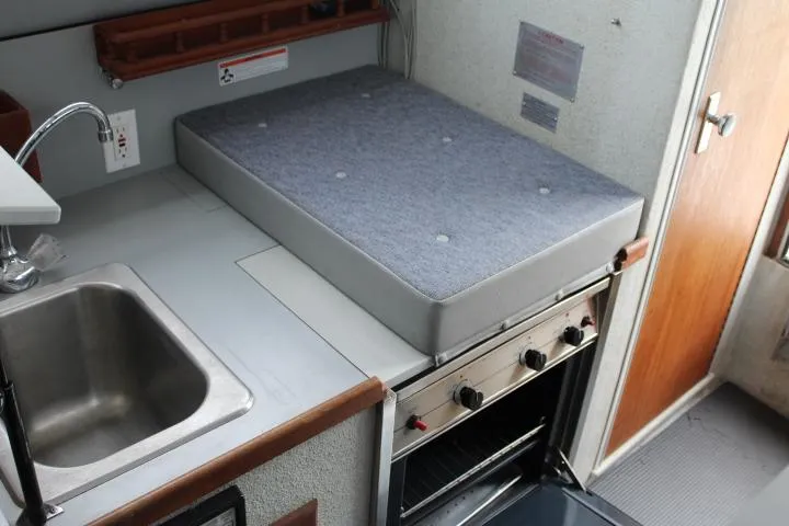 Slide: The Image of 1995 SeaSport 2400 Explorer interior with sink, stove, and cushioned counter space. - 46