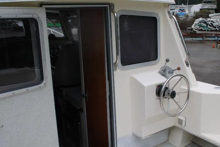 Slide: The Image of 1995 SeaSport 2400 Explorer boat helm with steering wheel and cabin entrance. - 6