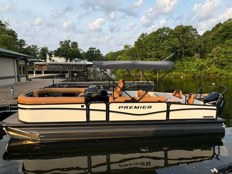 Slide: The Image of 2025 Premier 250 Sunsation Rear Social pontoon boat docked on a serene lake. - 1
