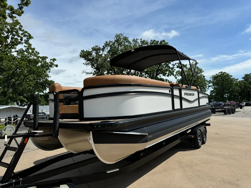 Slide: The Image of 2025 Premier 250 Sunsation Rear Social pontoon boat on trailer, under clear blue sky. - 10