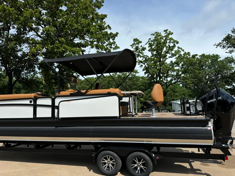 Slide: The Image of 2025 Premier 250 Sunsation Rear Social pontoon boat on trailer, parked outdoors. - 11