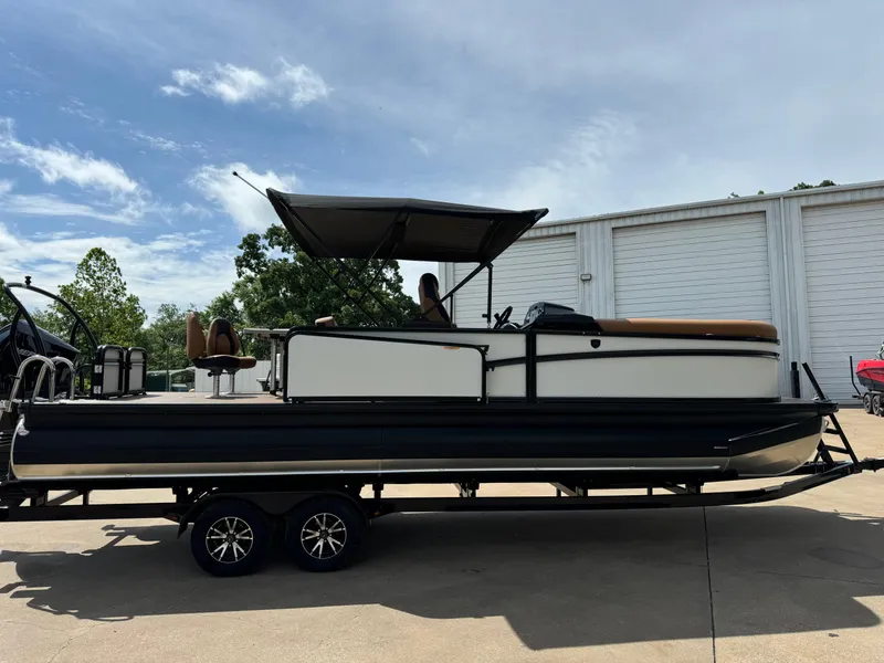 Slide: The Image of 2025 Premier 250 Sunsation Rear Social pontoon boat on trailer, parked outdoors. - 13