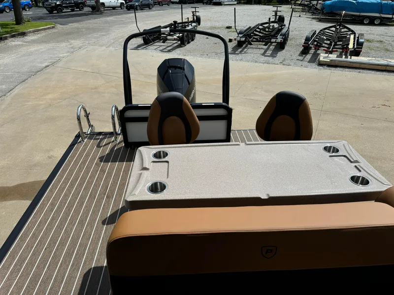 Slide: The Image of 2025 Premier 250 Sunsation Rear Social pontoon boat with seating and table, parked on a trailer. - 17