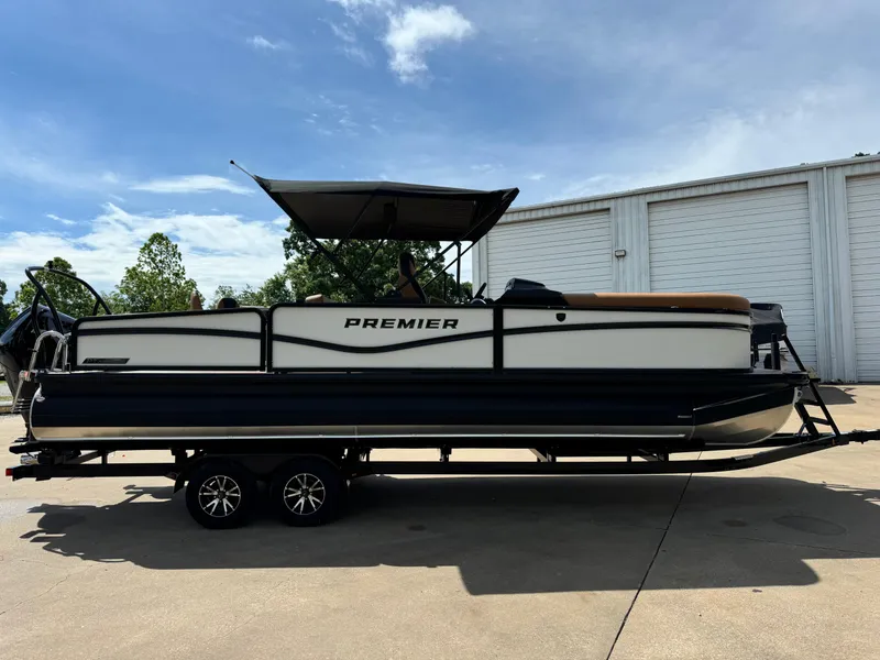 Slide: The Image of 2025 Premier 250 Sunsation Rear Social pontoon boat on trailer, parked outdoors. - 8