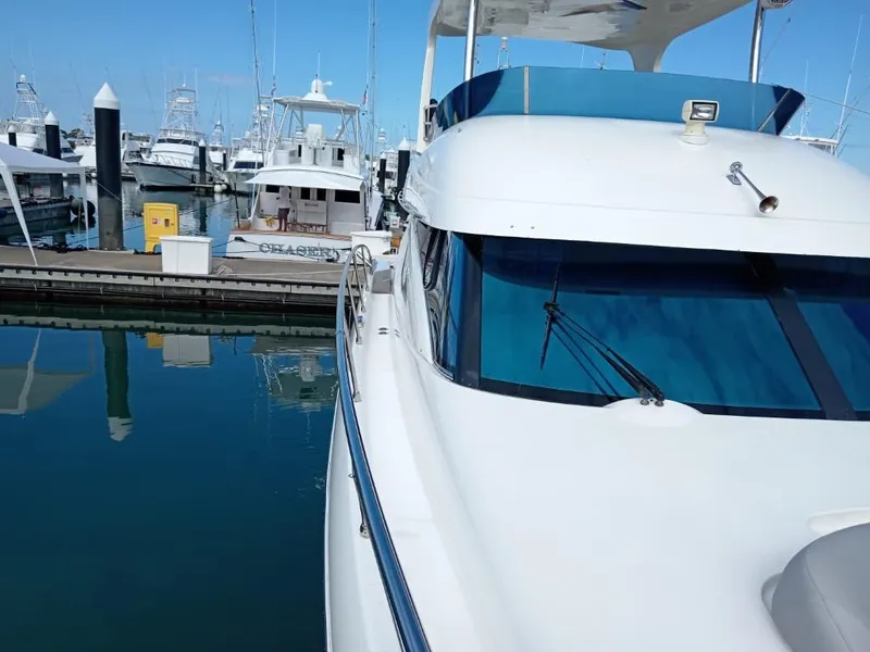 Slide: The Image of 2006 Prestige 46 yacht docked at marina, clear blue sky, calm water reflections. - 17