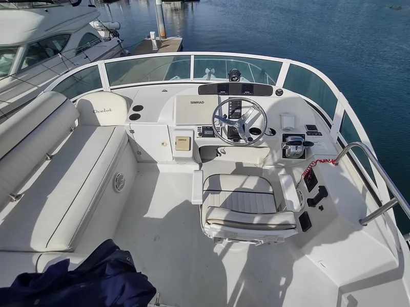 Slide: The Image of 2005 Glacier Bay 3490 Ocean Runner boat helm with seating, docked on calm water. - 27