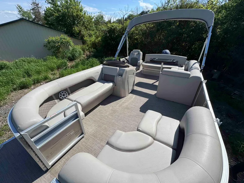 Slide: The Image of 2018 Bennington SX 22 SSBXP pontoon boat with spacious seating and canopy, surrounded by greenery. - 11