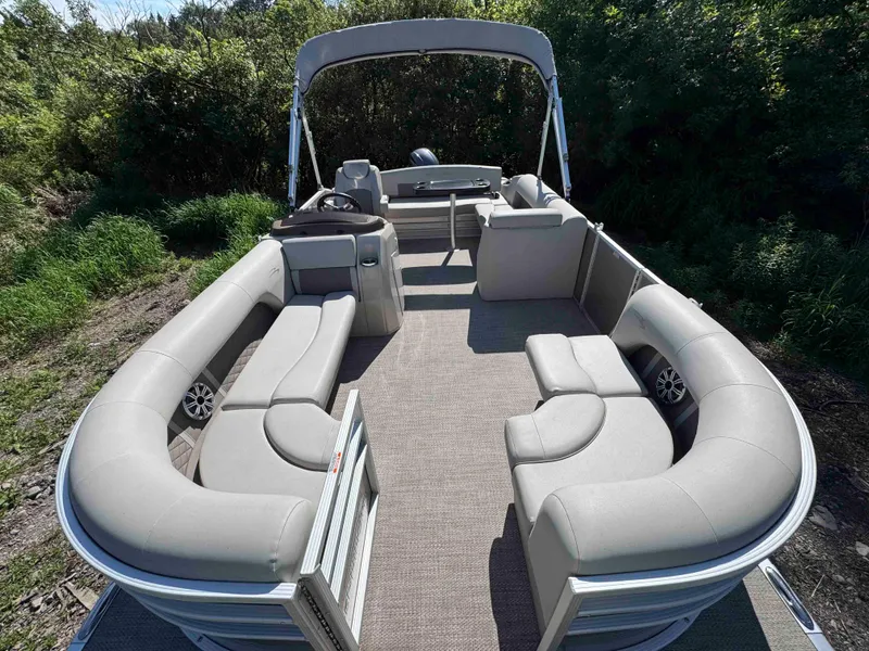 Slide: The Image of 2018 Bennington SX 22 SSBXP pontoon boat with spacious seating and canopy, surrounded by greenery. - 5