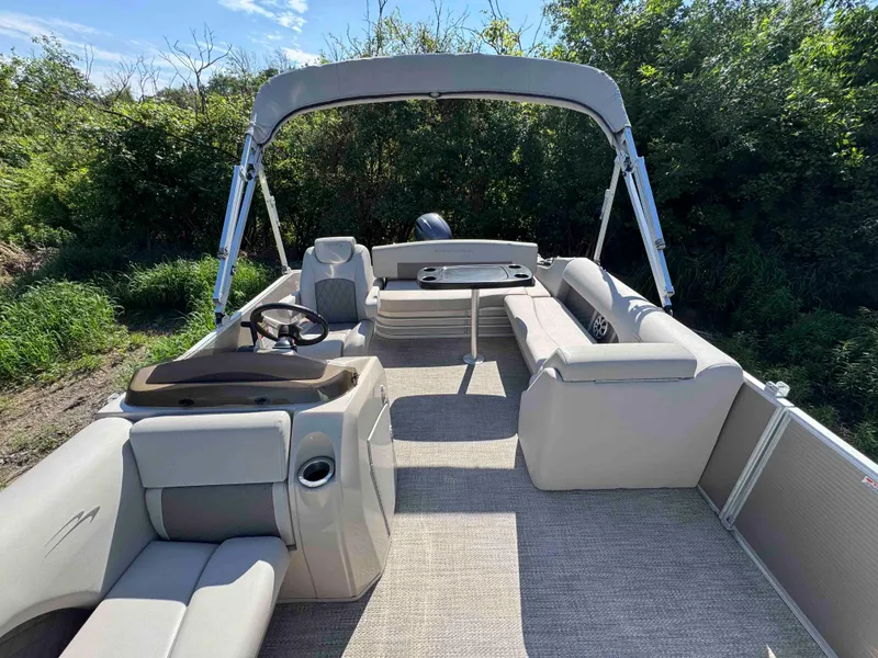 Slide: The Image of 2018 Bennington SX 22 SSBXP pontoon boat interior with seating and canopy, surrounded by greenery. - 8