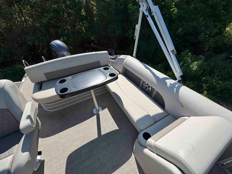 Slide: The Image of 2018 Bennington SX 22 SSBXP pontoon boat interior with seating and table, surrounded by greenery. - 9