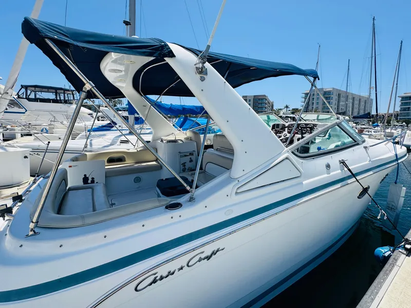 Slide: The Image of 2000 Chris-Craft 308 Express Cruiser docked at marina, featuring sleek design and blue canopy. - 2