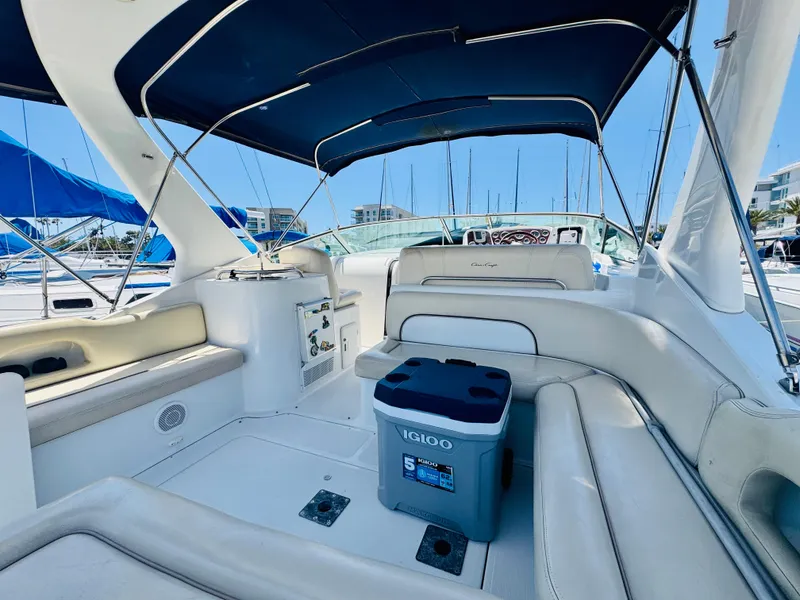 Slide: The Image of 2000 Chris-Craft 308 Express Cruiser interior with seating and cooler under blue canopy. - 20