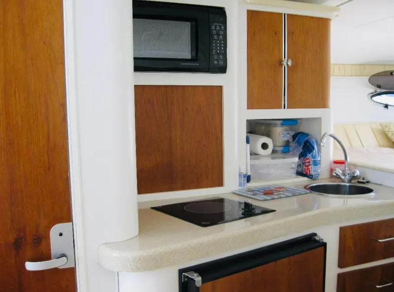 Slide: The Image of 2000 Chris-Craft 308 Express Cruiser kitchen with microwave, sink, and wooden cabinets. - 30