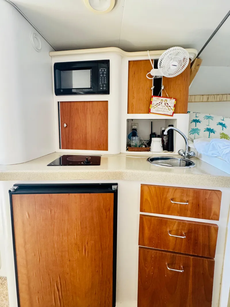 Slide: The Image of Compact kitchen in 2000 Chris-Craft 308 Express Cruiser with microwave, sink, and wooden cabinets. - 38
