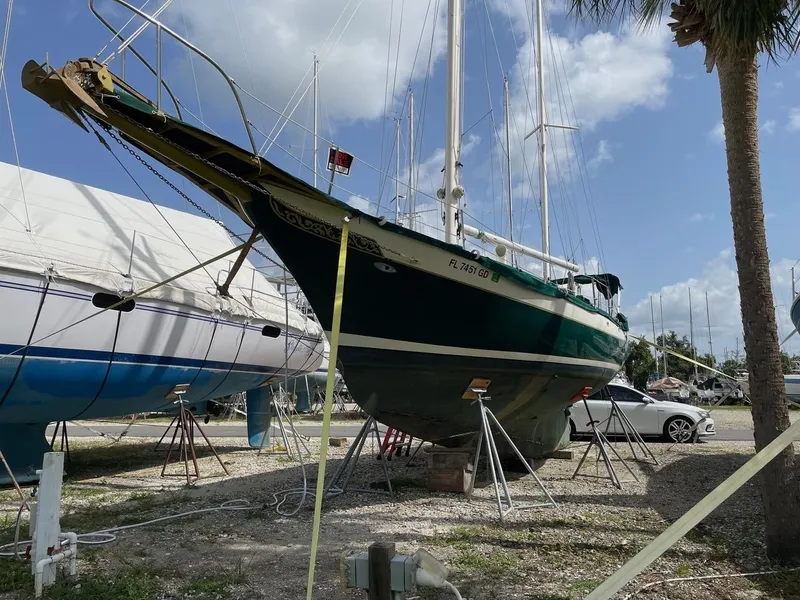Slide: The Image of 1974 Cheoy Lee Clipper Ketch sailboat on dry dock under a partly cloudy sky. - 16