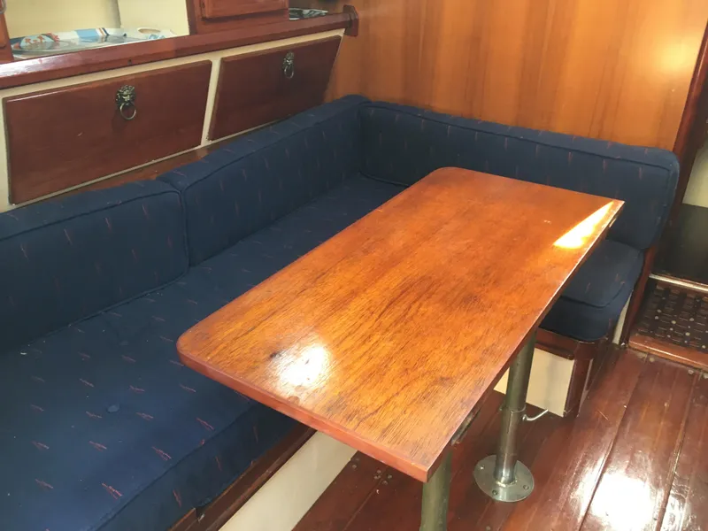 Slide: The Image of Interior of 1974 Cheoy Lee Clipper Ketch with wooden table and blue cushioned seating. - 4