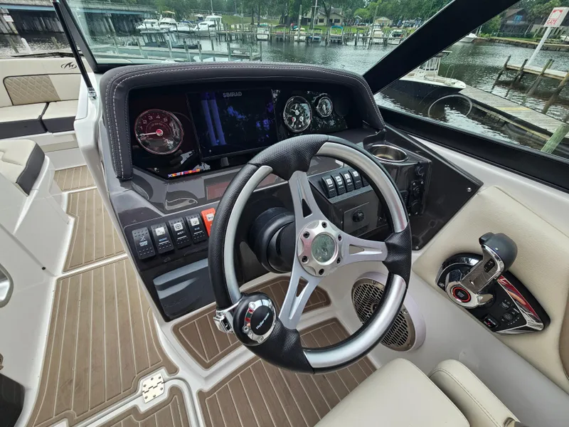 Slide: The Image of 2023 Monterey M-65 boat dashboard with steering wheel and control panel, docked by the water. - 14