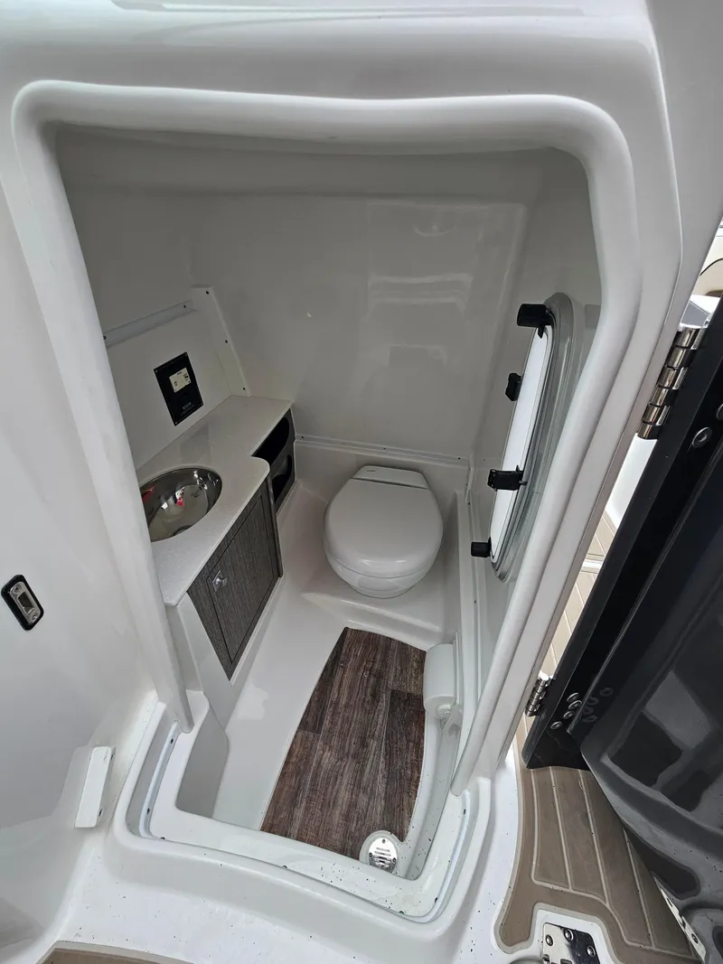 Slide: The Image of Compact bathroom in 2023 Monterey M-65 boat, featuring toilet, sink, and storage. - 16