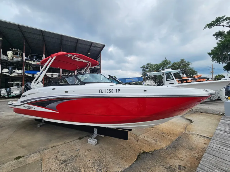 Slide: The Image of 2023 Monterey M-65 boat with red and white design, docked outdoors under cloudy skies. - 5