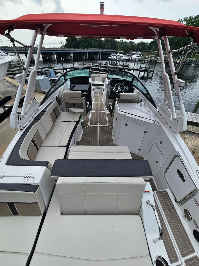 Slide: The Image of 2023 Monterey M-65 boat with red canopy, spacious seating, and modern design at a marina. - 8