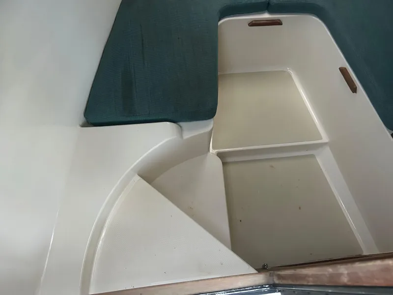 Slide: The Image of 1998 Carolina Classic 25 Express cabin interior with cushioned seating and storage area. - 15