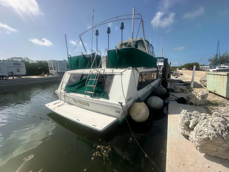 Slide: The Image of 1989 Bluewater 51' Coastal Cruiser docked, featuring green covers and a sunny sky backdrop. - 2