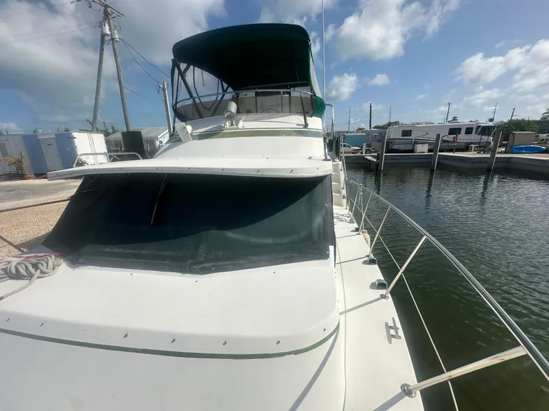Slide: The Image of 1989 Bluewater 51' Coastal Cruiser docked, featuring a green canopy and sleek design. - 4